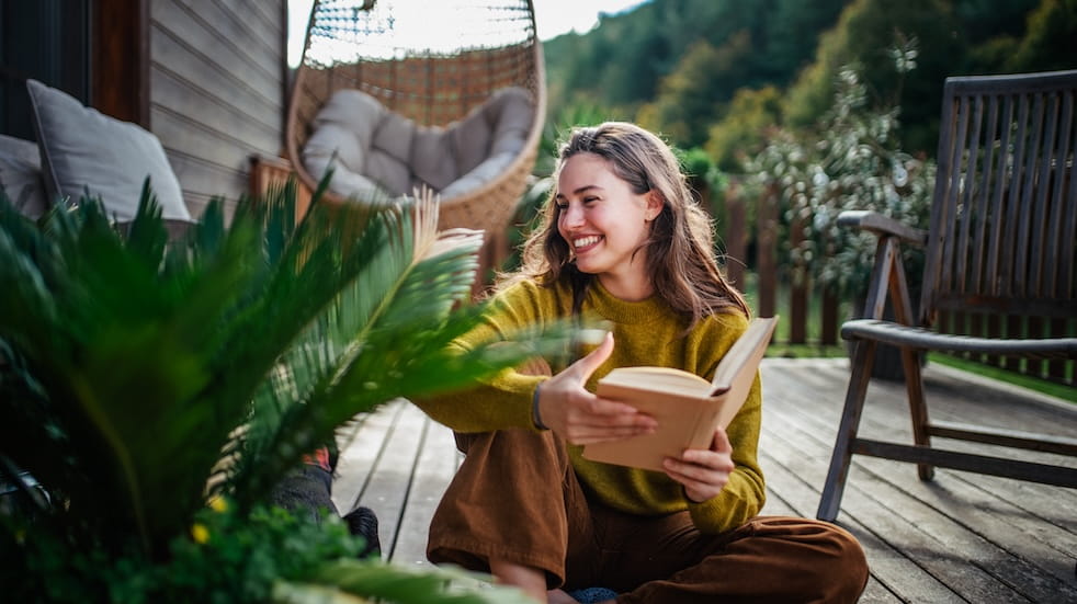Woman sitting on patio, reading book